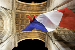 French flag flying under Arc de Triomphe